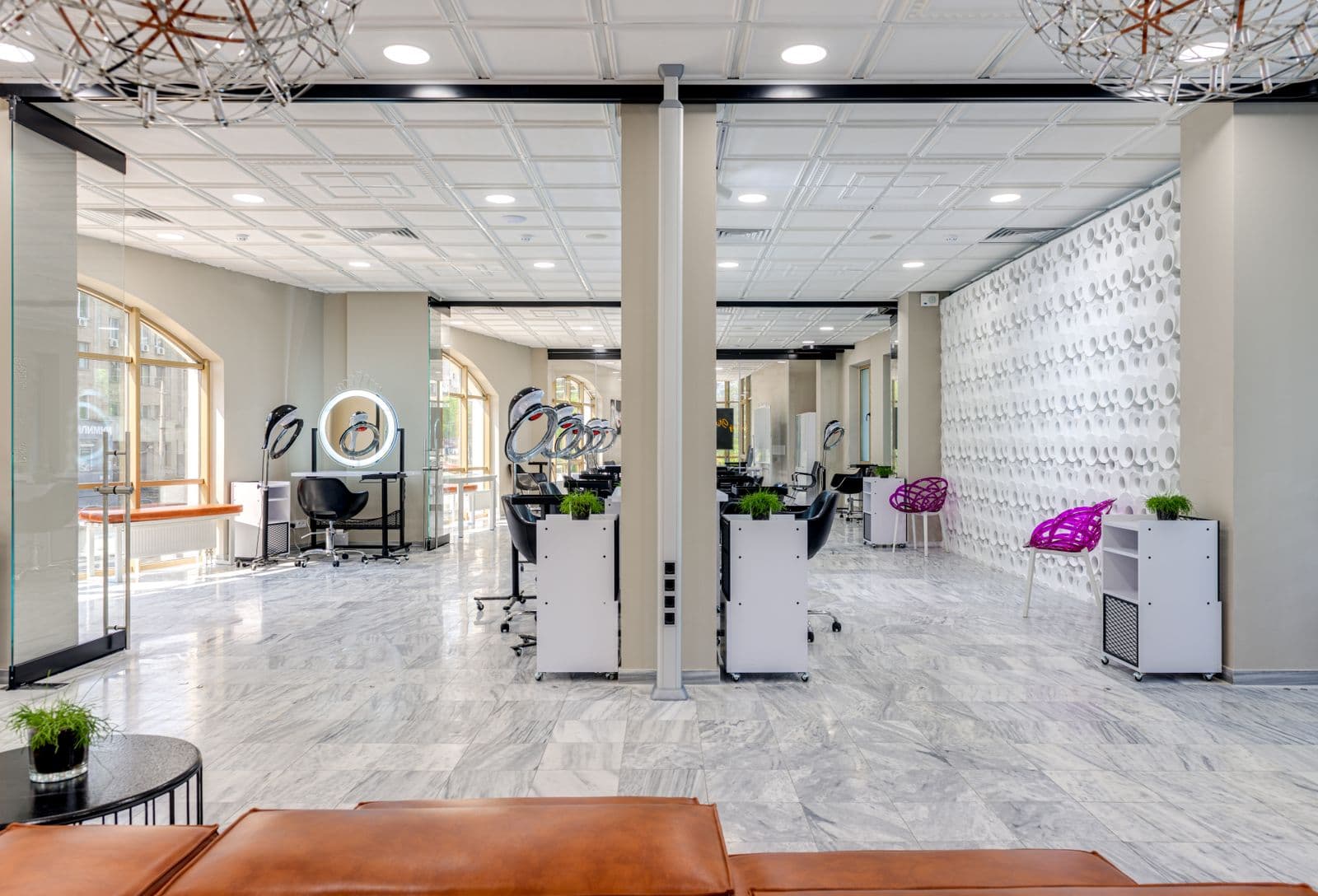 Un salon de coiffure lumineux avec de grands miroirs et des fauteuils contemporains