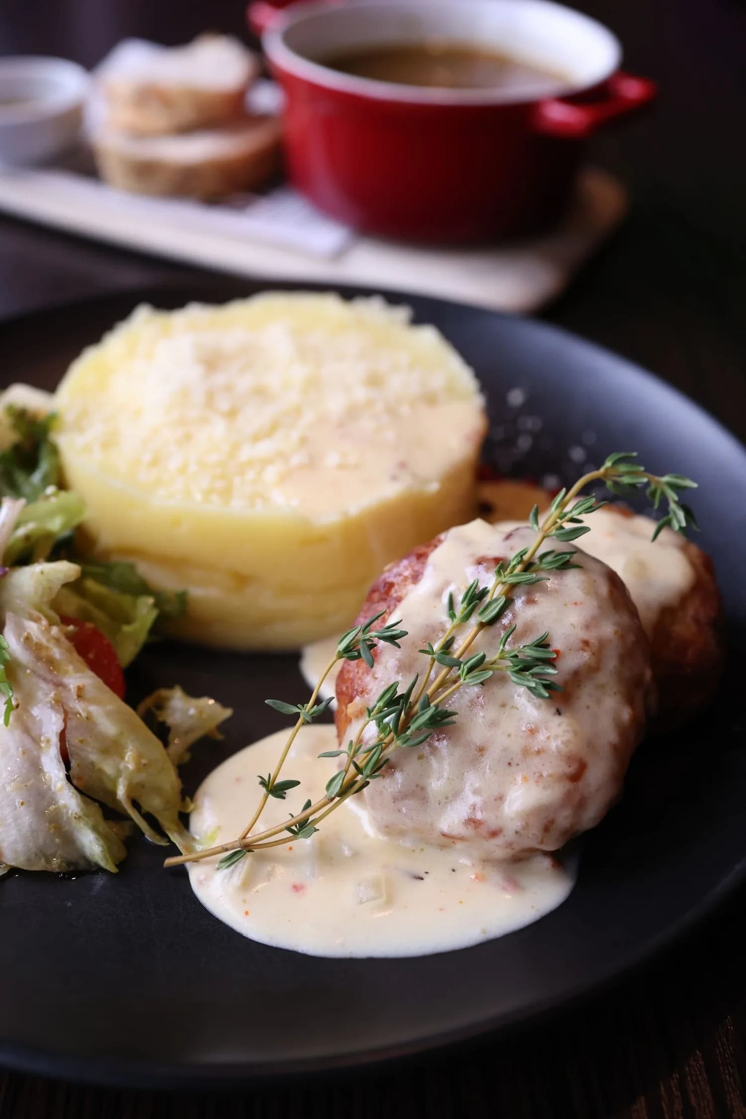 Une assiette de volaille, légumes et sauce, dressée sur une table de restaurant
